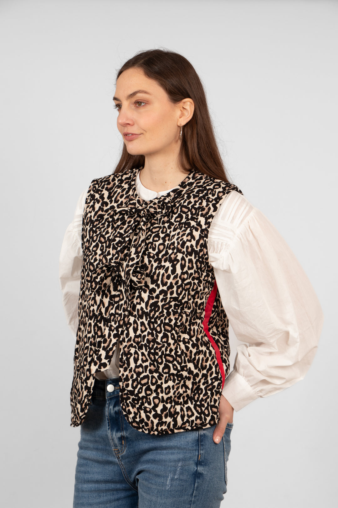 model wearing a natural animal print quilted gilet with front ties and a red striped which runs vertically down the side of the piece.