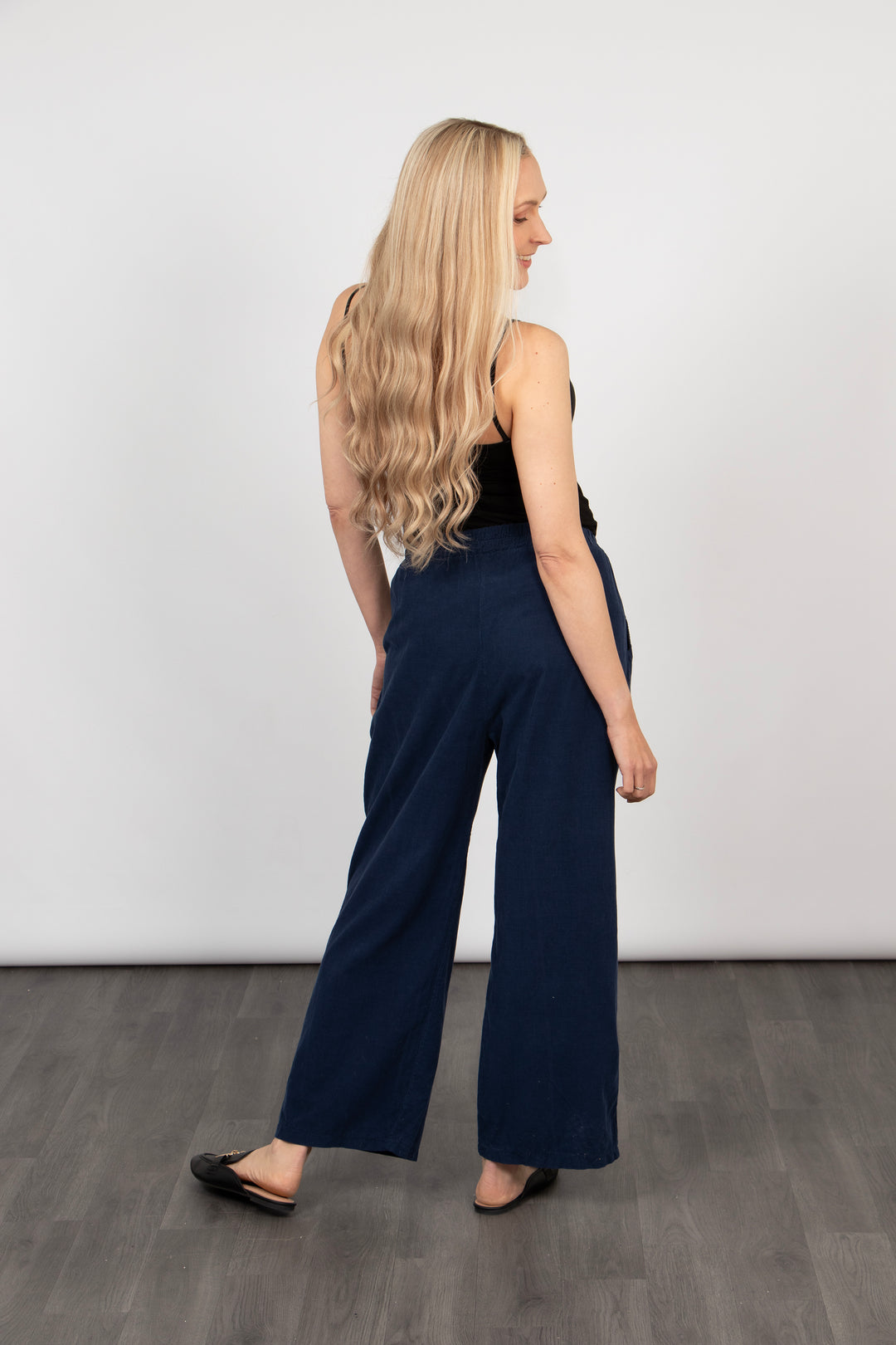 model showing the back of the navy blue baby cord trousers, showing the wide leg design of the piece