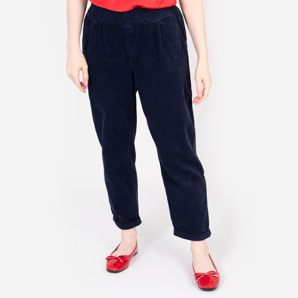 model wearing navy blue babycord trousers, they are relaxed fitting and have an elasticated waist band