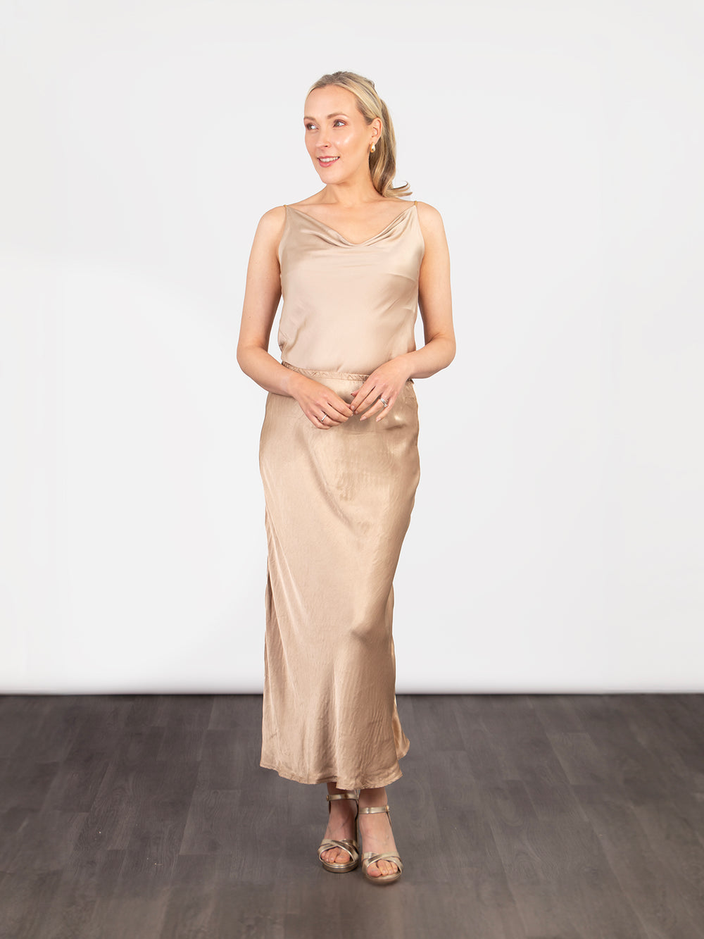 model wearing a midi length gold slip skirt with an elasticated waist