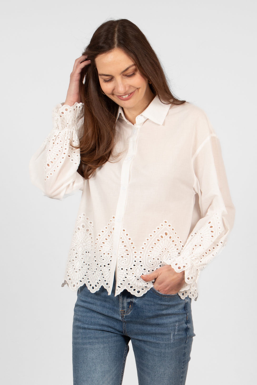 model wearing a lightweight white cotton shirt with a detailed broderie anglaise design on the cuffs and lower quarter of the bodice.