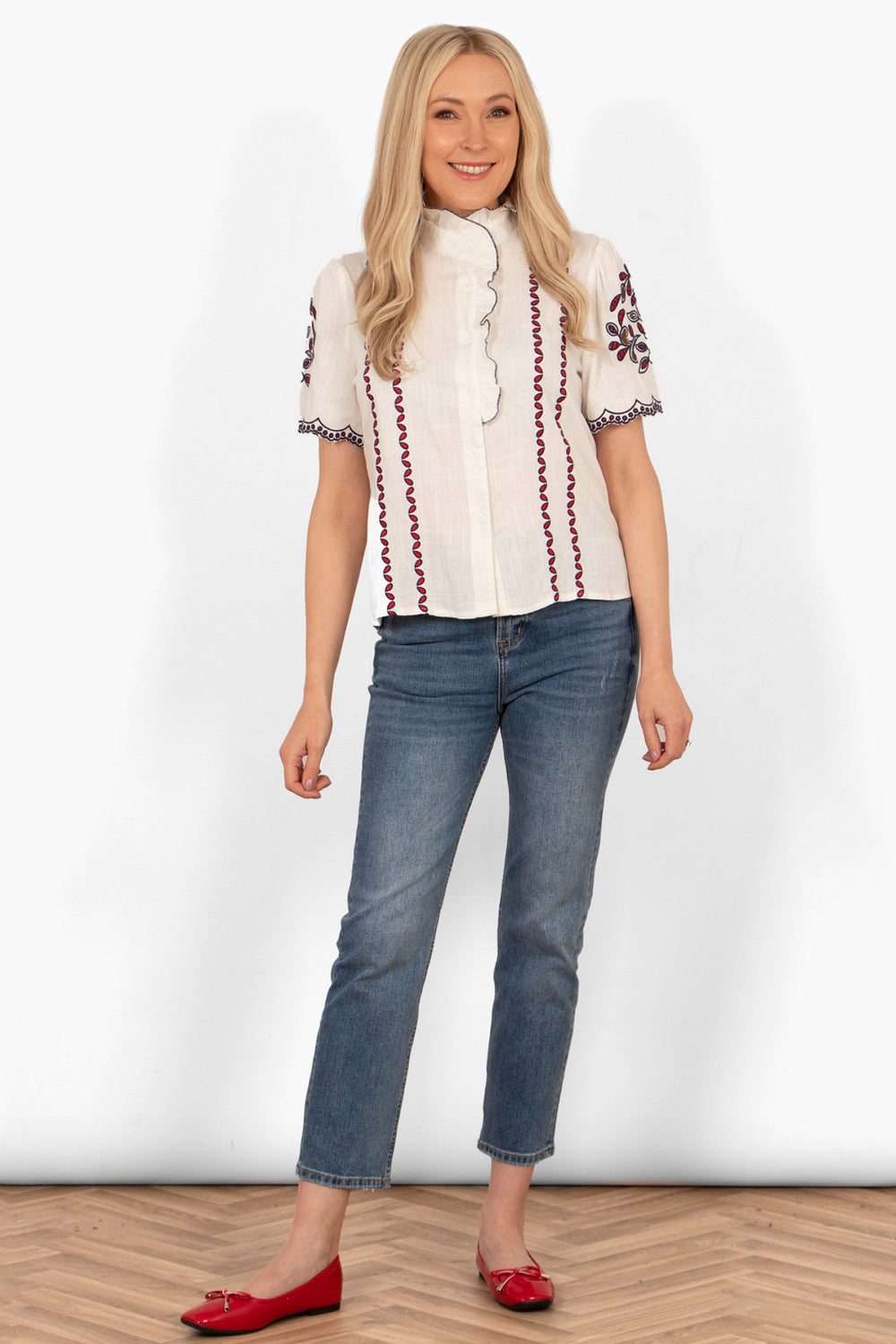 evelyn-short-sleeve-shirt-white-red-floral-embroidery-styled-with-blue-jeans-red-shoes