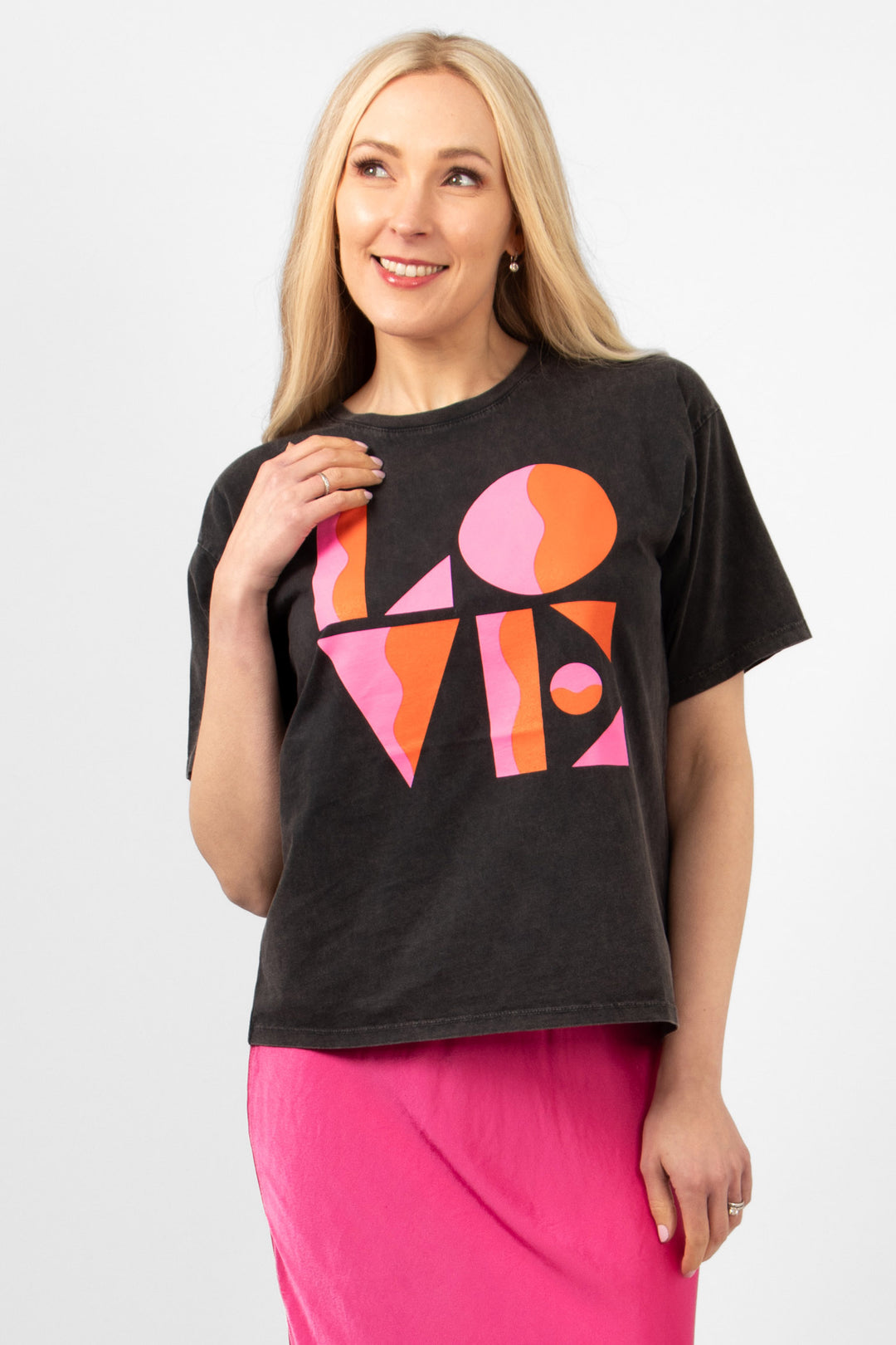 model wearing a black cotton t-shirt with a the word love printed boldly in pink and coral on the front. the t-shirt has a round neck and loose short sleeves.