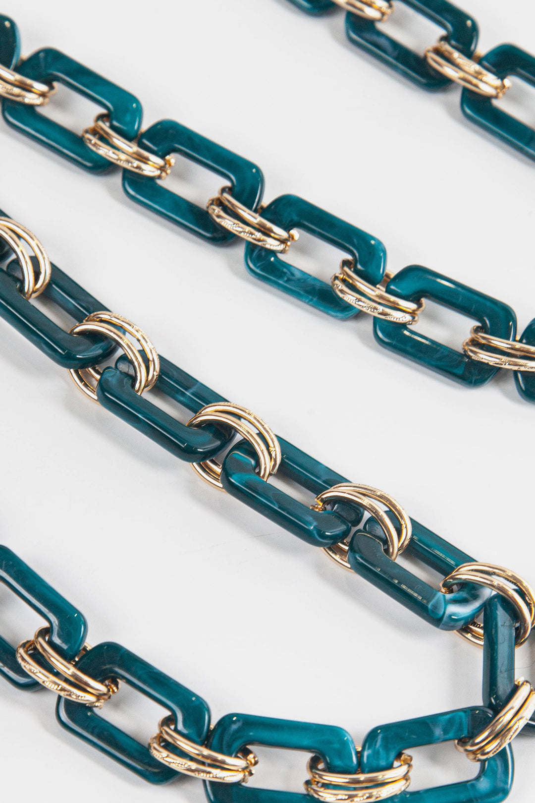 close up of the teal square link acrylic bag strap each link is adjoined by two gold metal hoops