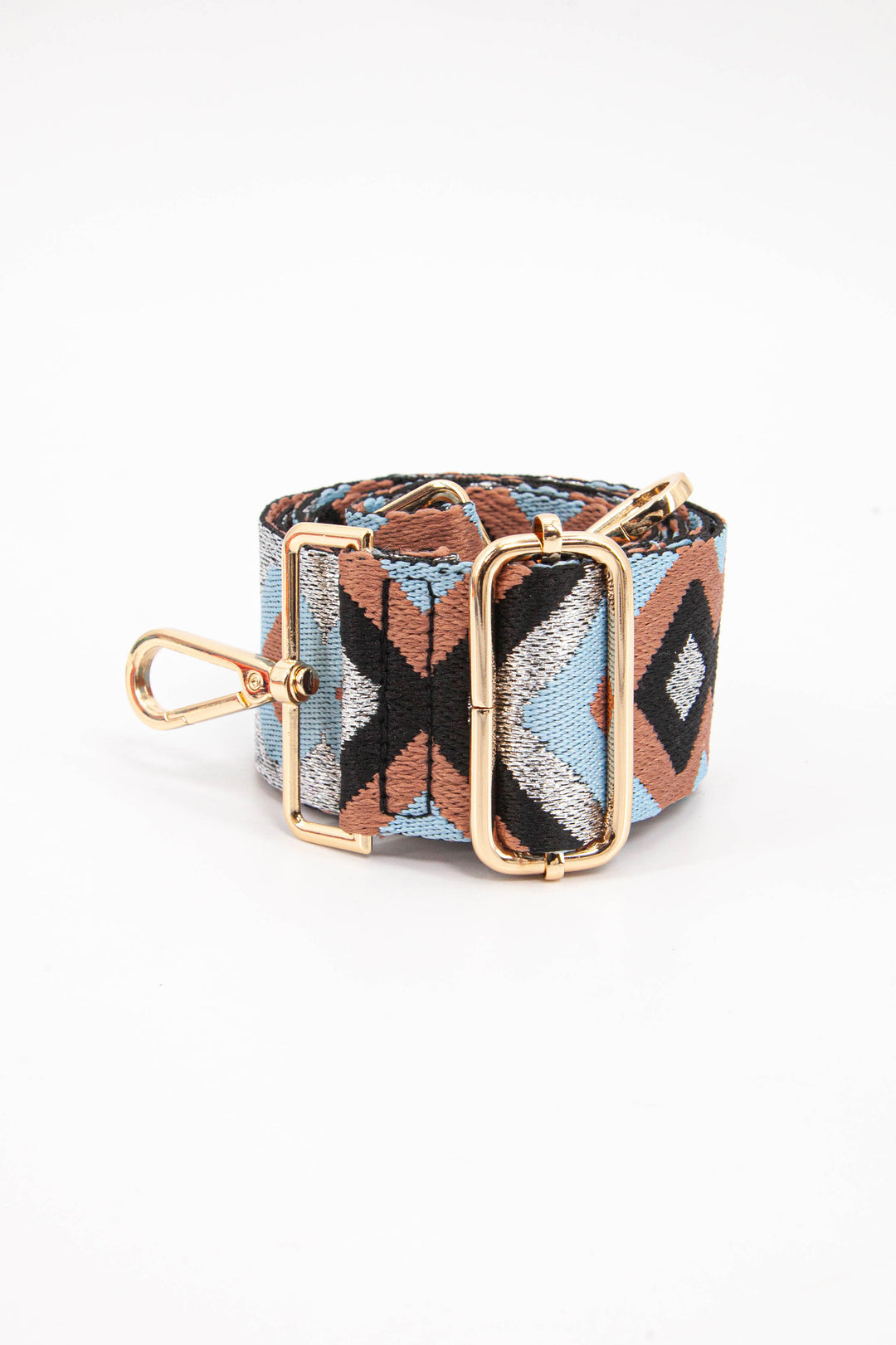 close up of the gold adjustment buckle on the silver, pink and blue aztec pattern bag strap