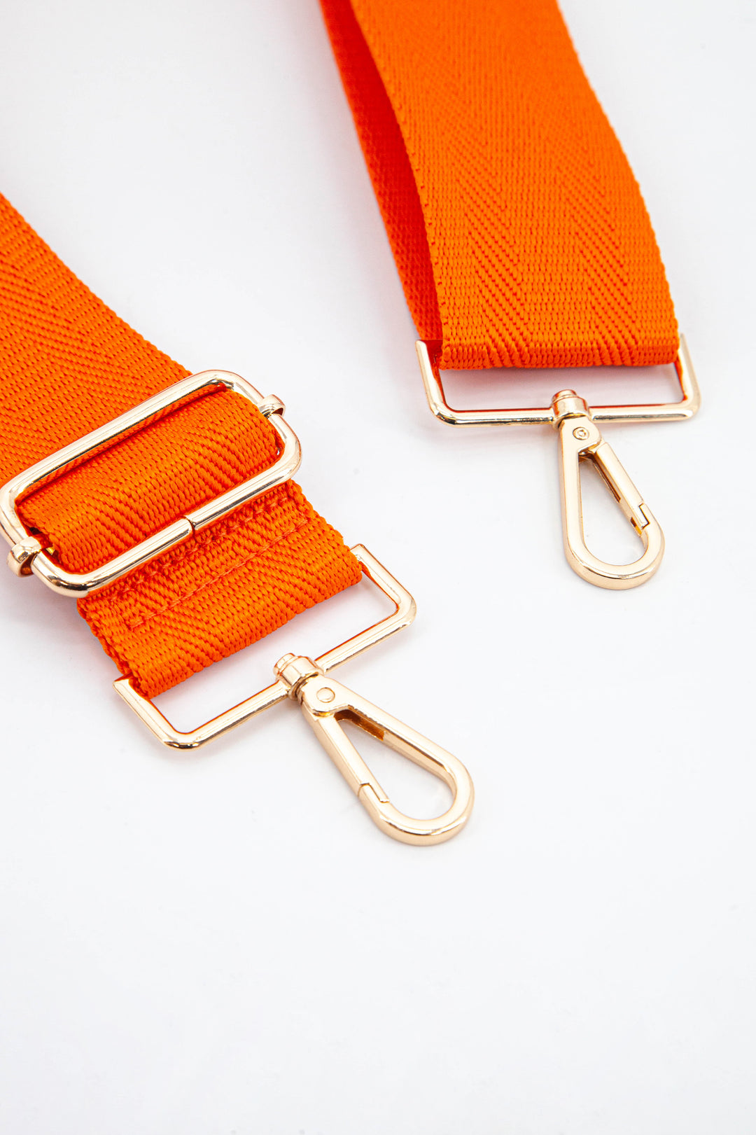 close up of the gold snap hook attachments and the orange colour of the strap