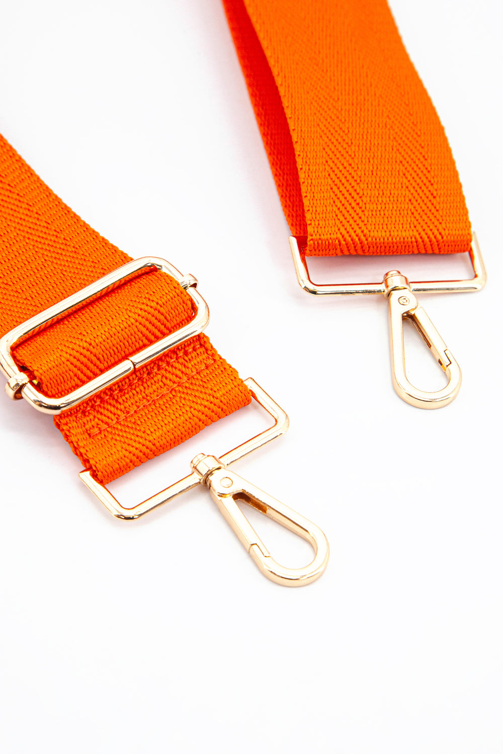 close up of the gold snap hook attachments and the orange colour of the strap