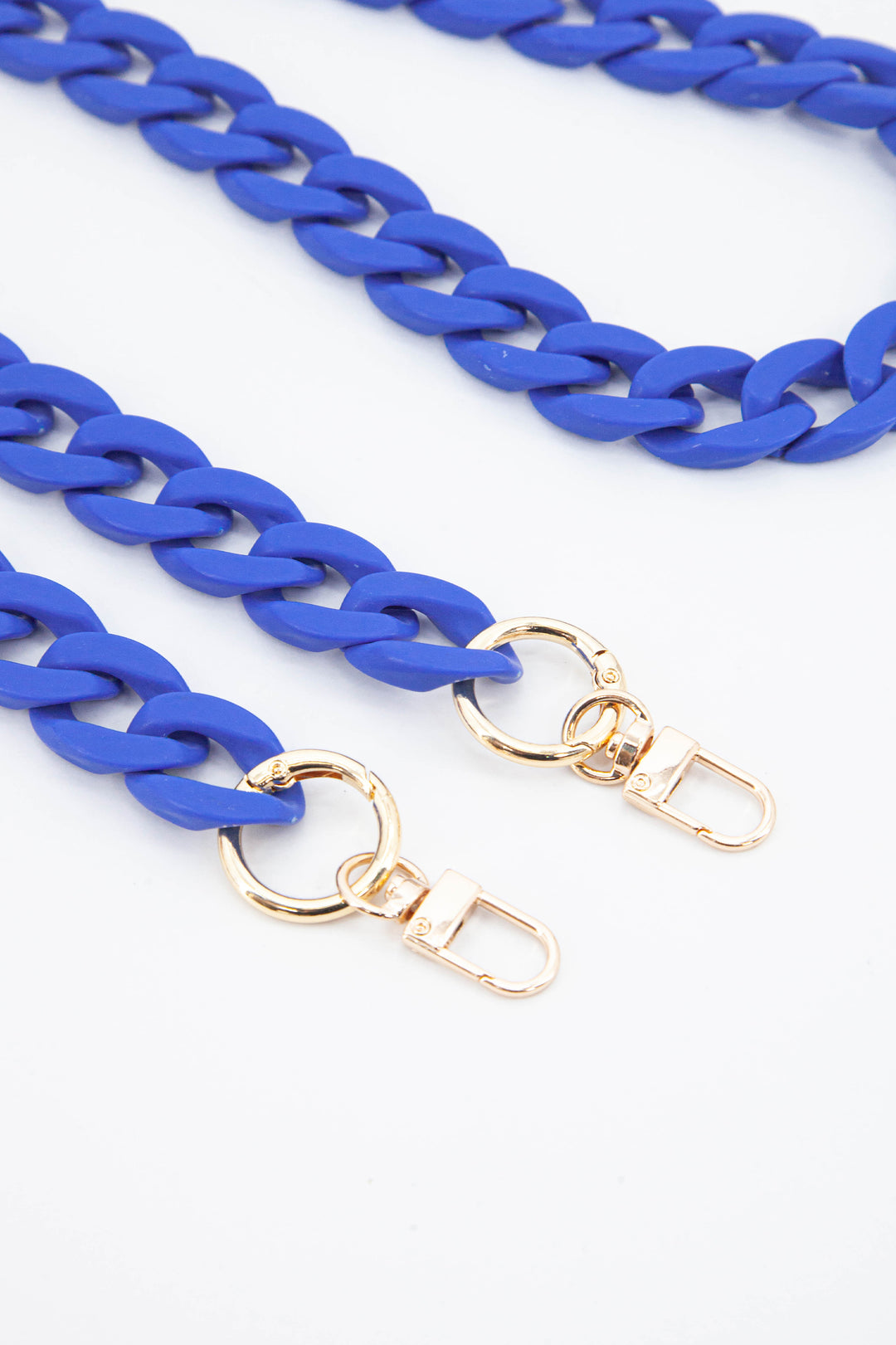 close up of the gold clip on attachments and a close up of the blue cuban style acrylic bag strap