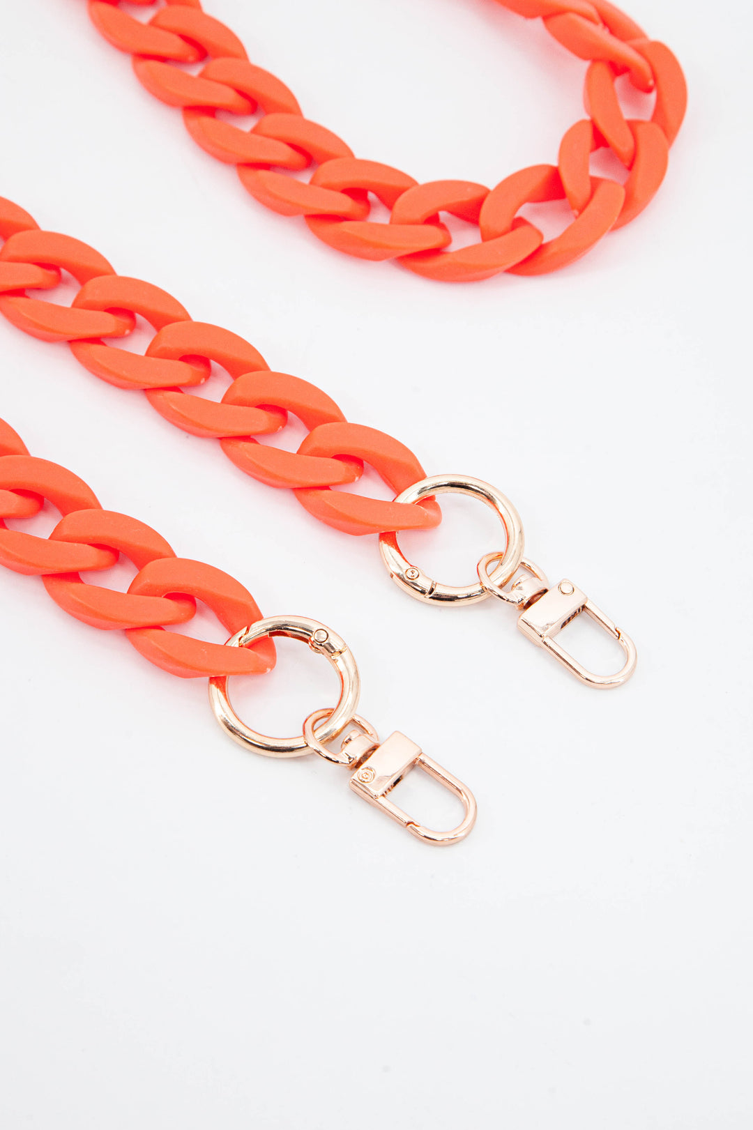 close up of the gold clip on attachments and a close up of the orange cuban style acrylic bag strap