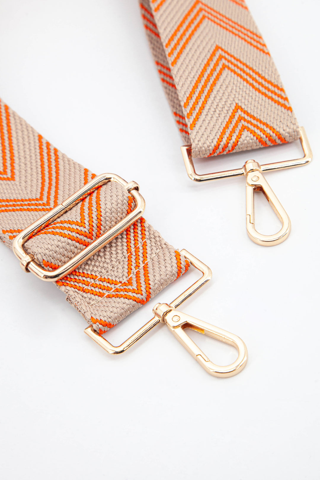 close up of the gold clip on snap hook attachments and the orange woven chevron material