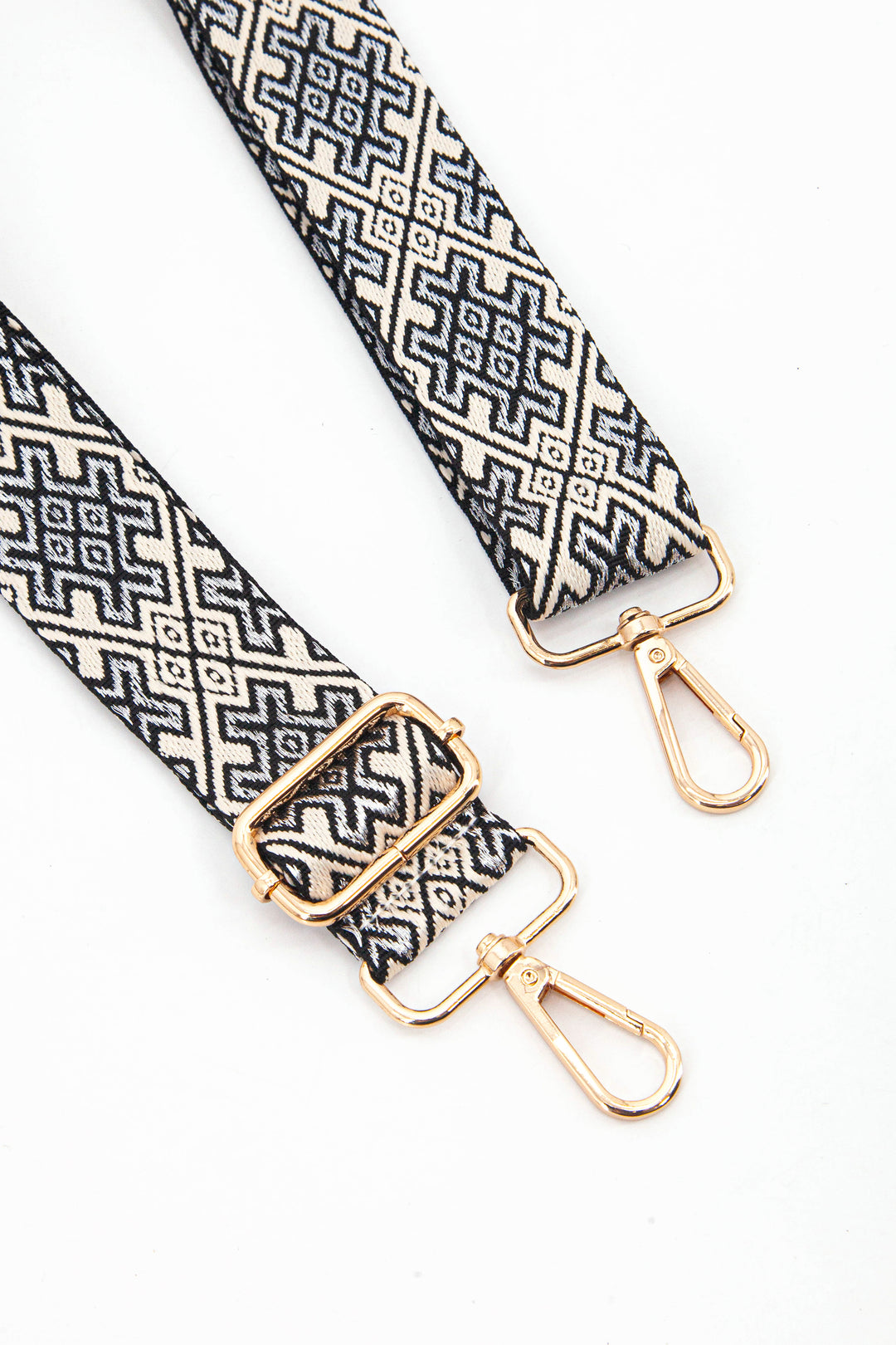 close up of the gold clip on snap hook and adjustable buckle on the bag strap