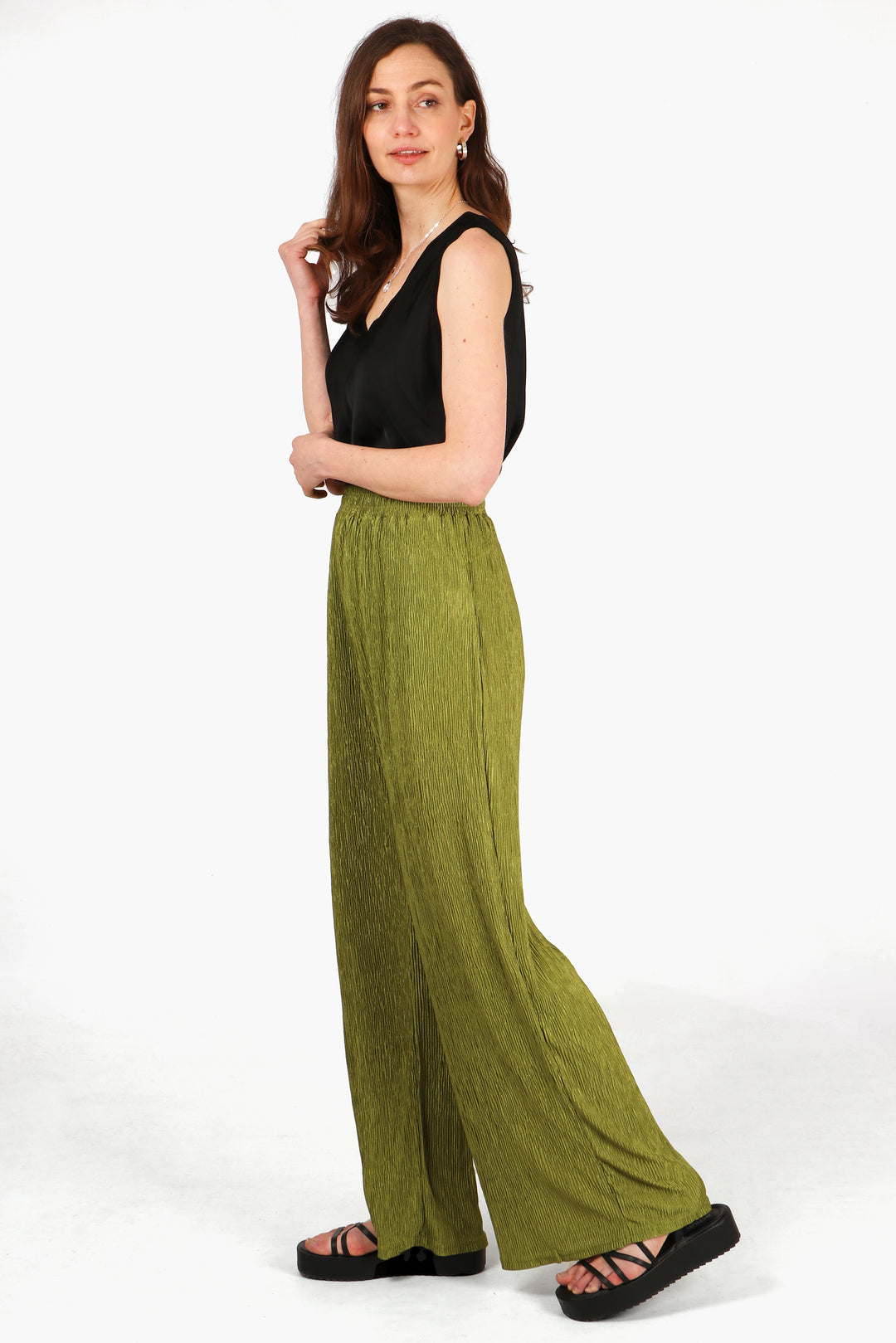 model wearing a pair of plisse material long trousers in an olive green colour