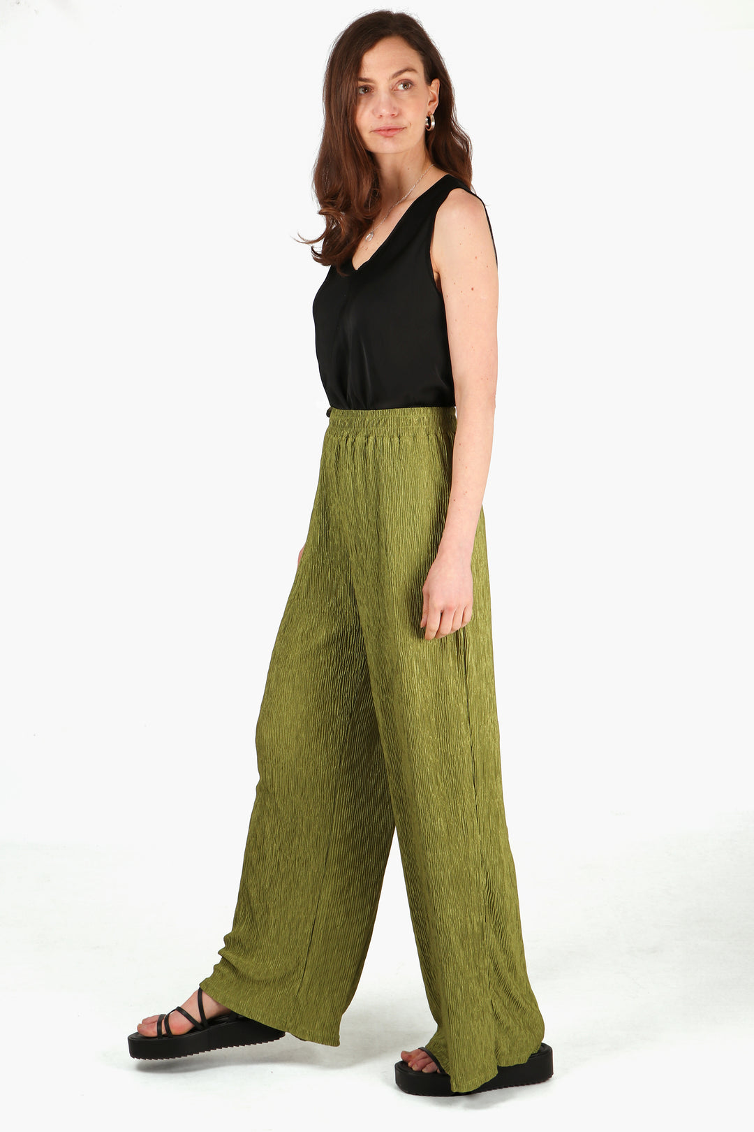 model wearing a pair of plisse material long trousers in an olive green colour