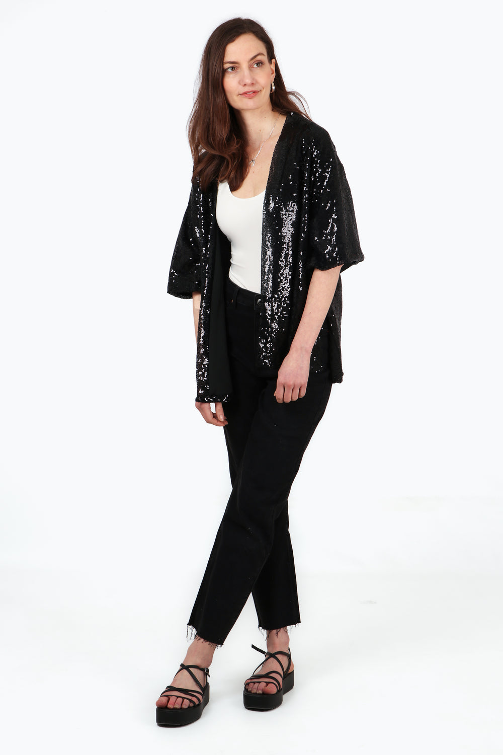 model wearing a black sequin evening kimono jacket with 3/4 sleeves and an all over sparkle effect