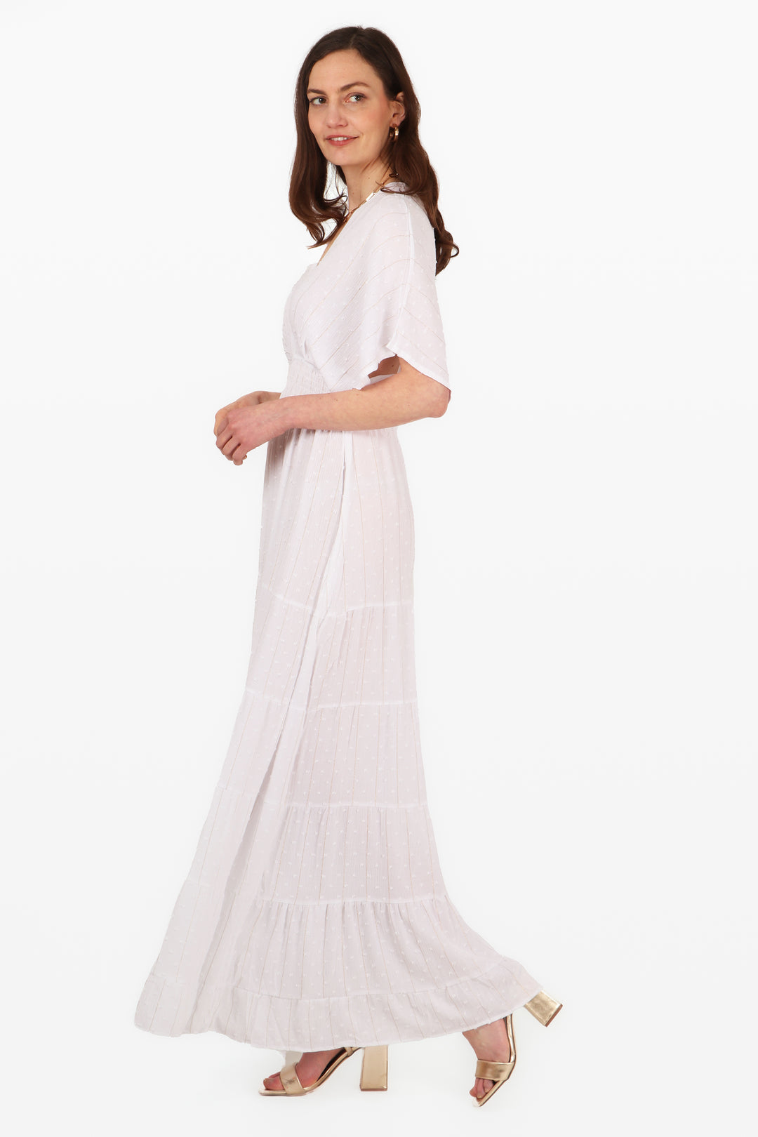 model wearing a white maxi length kaftan dress with a metallic gold foil stripe detail and dobby material