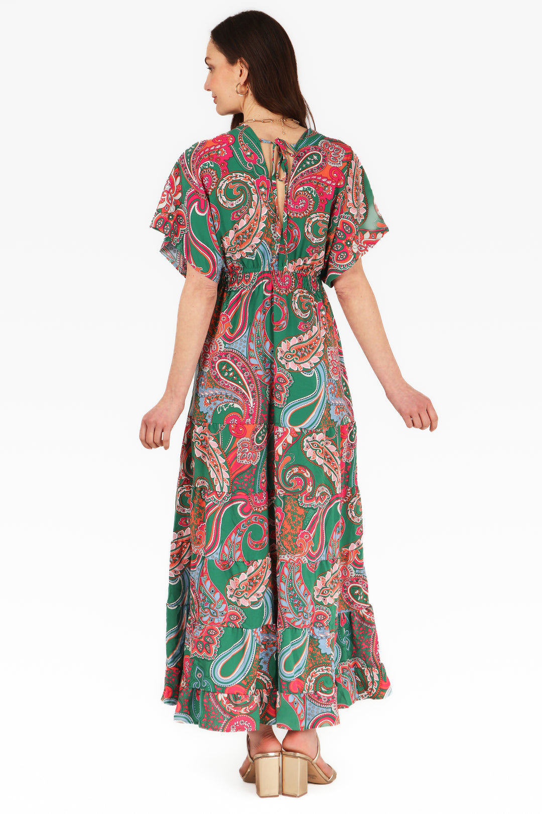 model showing the back of the green and pink paisley kaftan dress, showing the tie at the back of the neck and the plunging V neck at the back