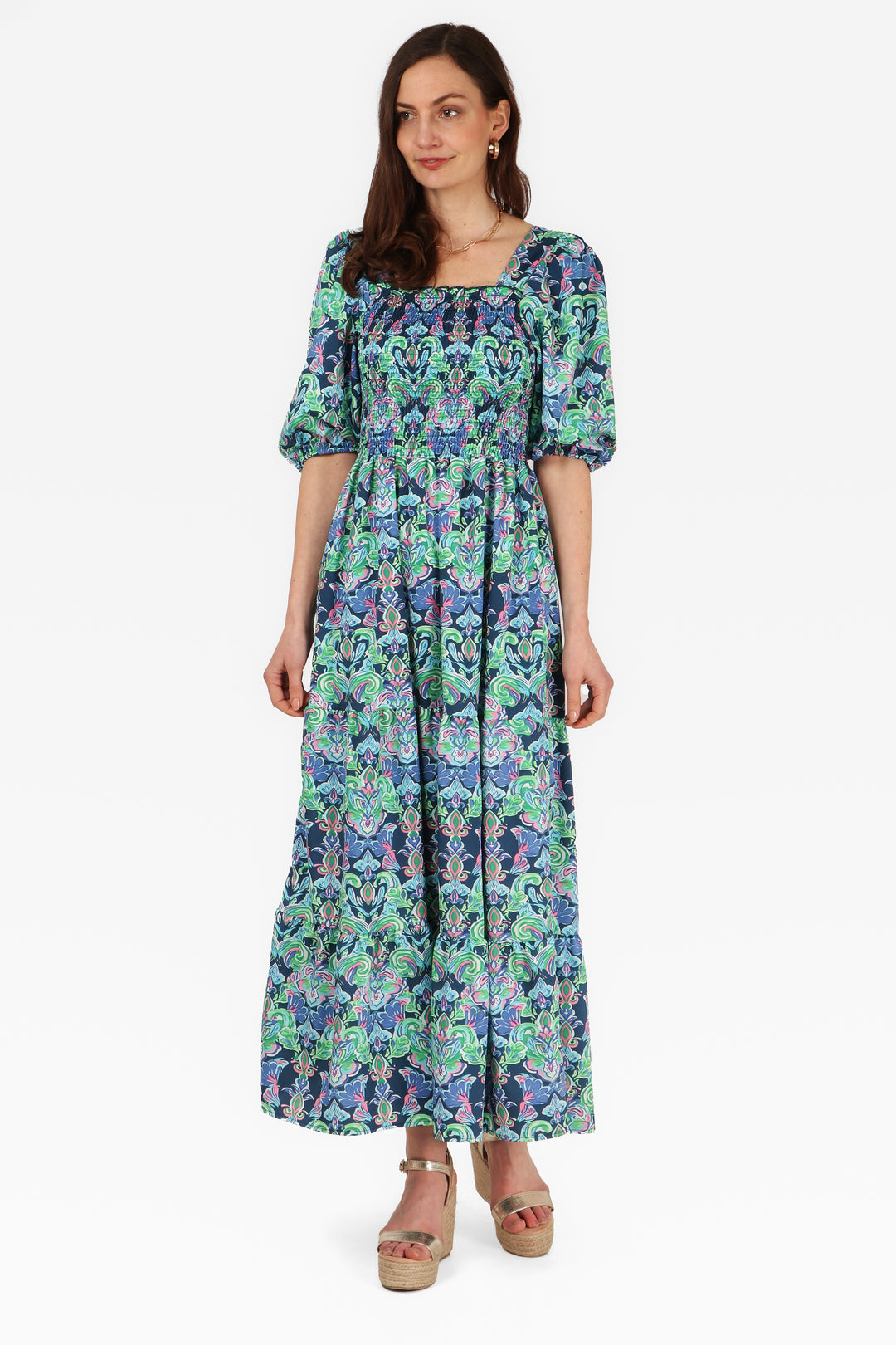 model wearing a blue tiered milkmaid maxi dress with short sleeves and an all over fleur de lis floral print 1