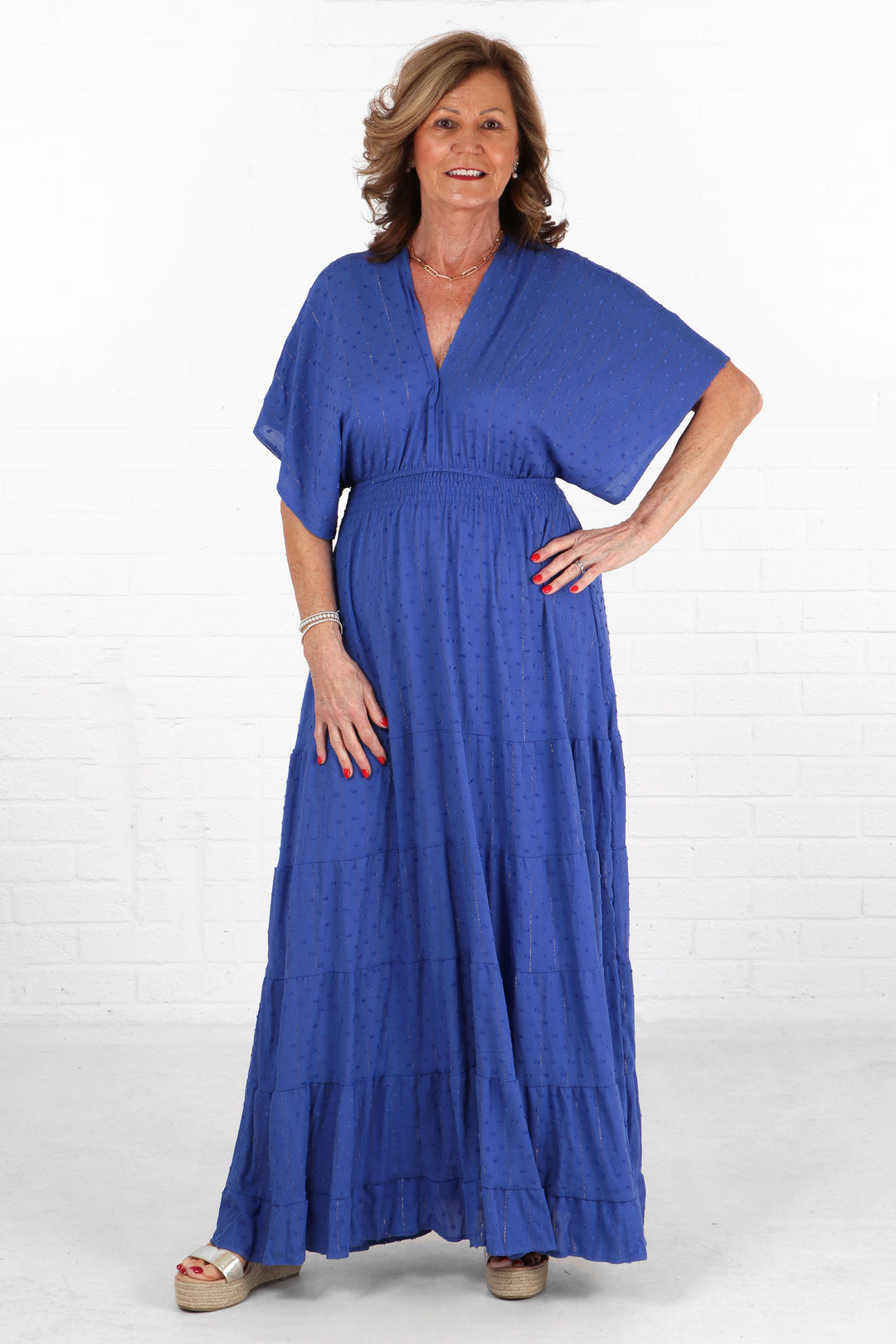 model wearing a royal blue maxi length kaftan dress with a metallic gold foil stripe detail and dobby material