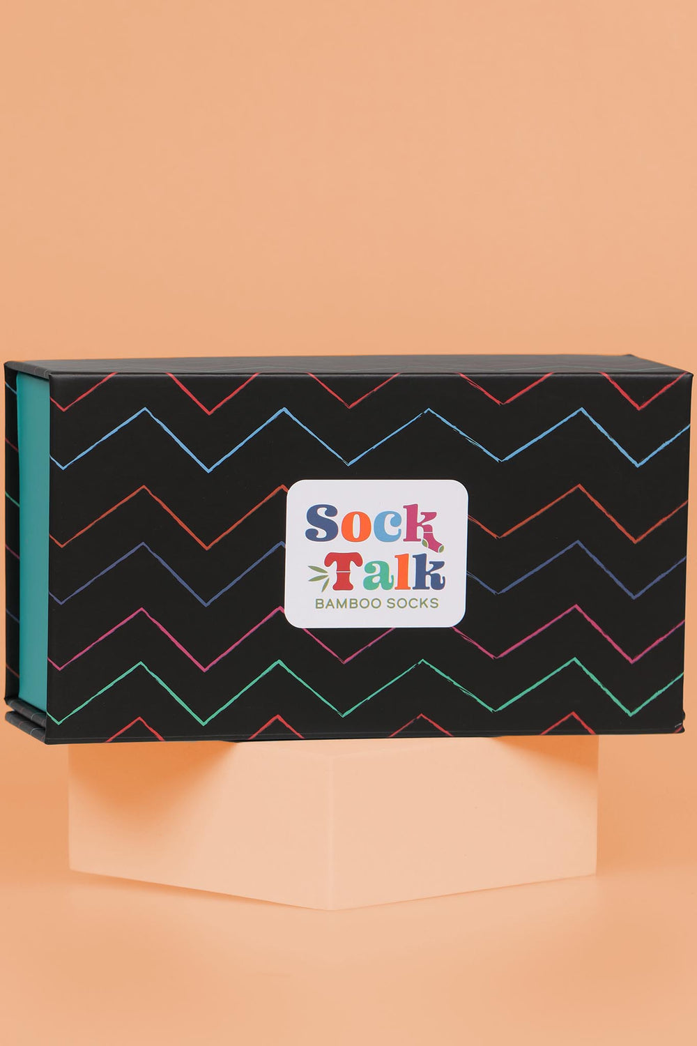 close up of the artistically designed gift box which is black with multicoloured zig zag pinstripes