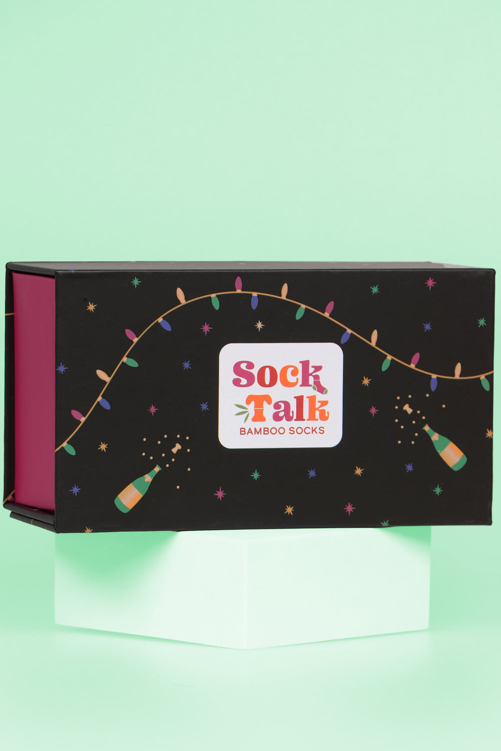 black gift box with a design of multicoloured party lights, champagne bottles and stars