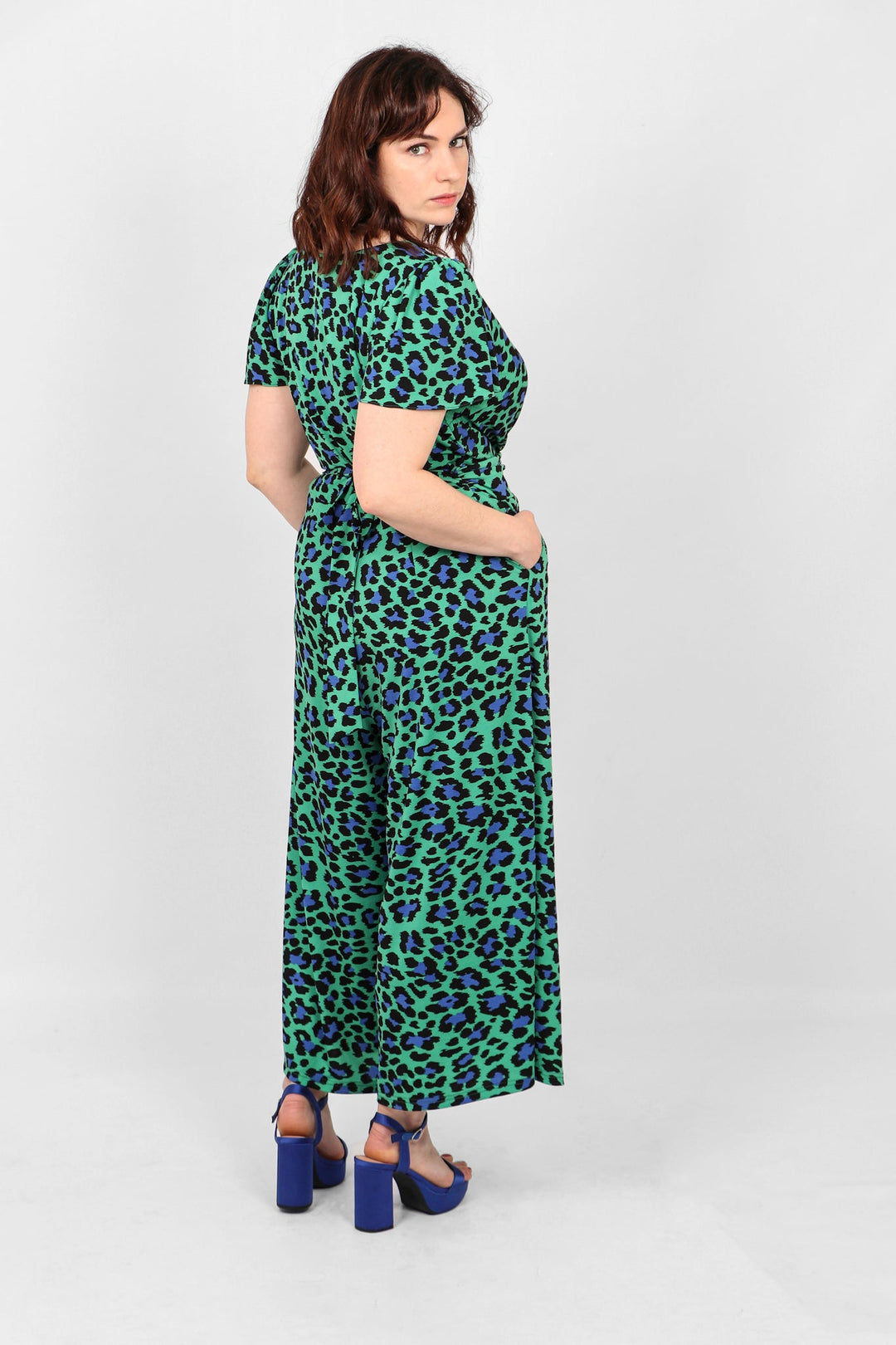 Model showing back of green and navy blue jumpsuit with tie waist