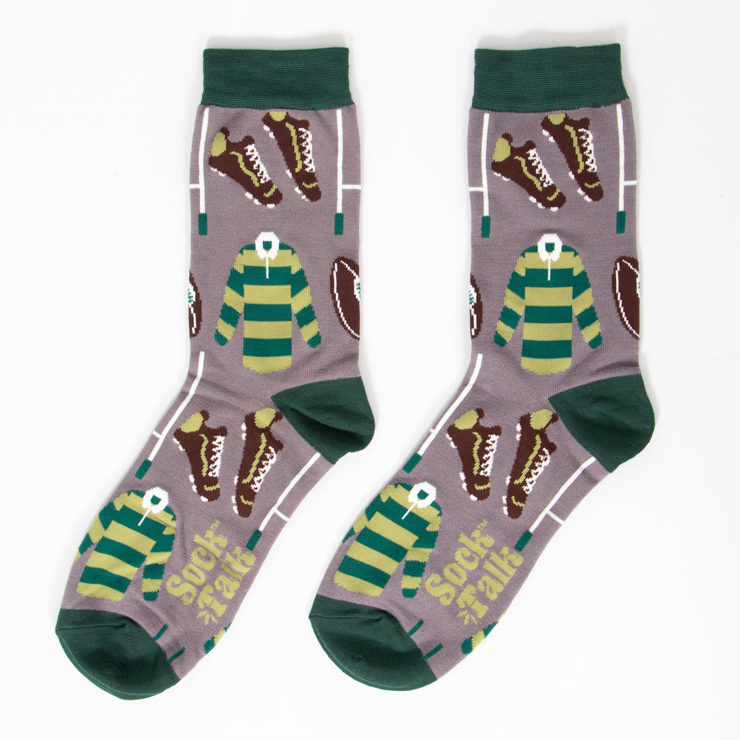 showing the socks laying flat, they have a grey background and dark green heel, toe and cuff. the rugby themed pattern covers the whole of the design