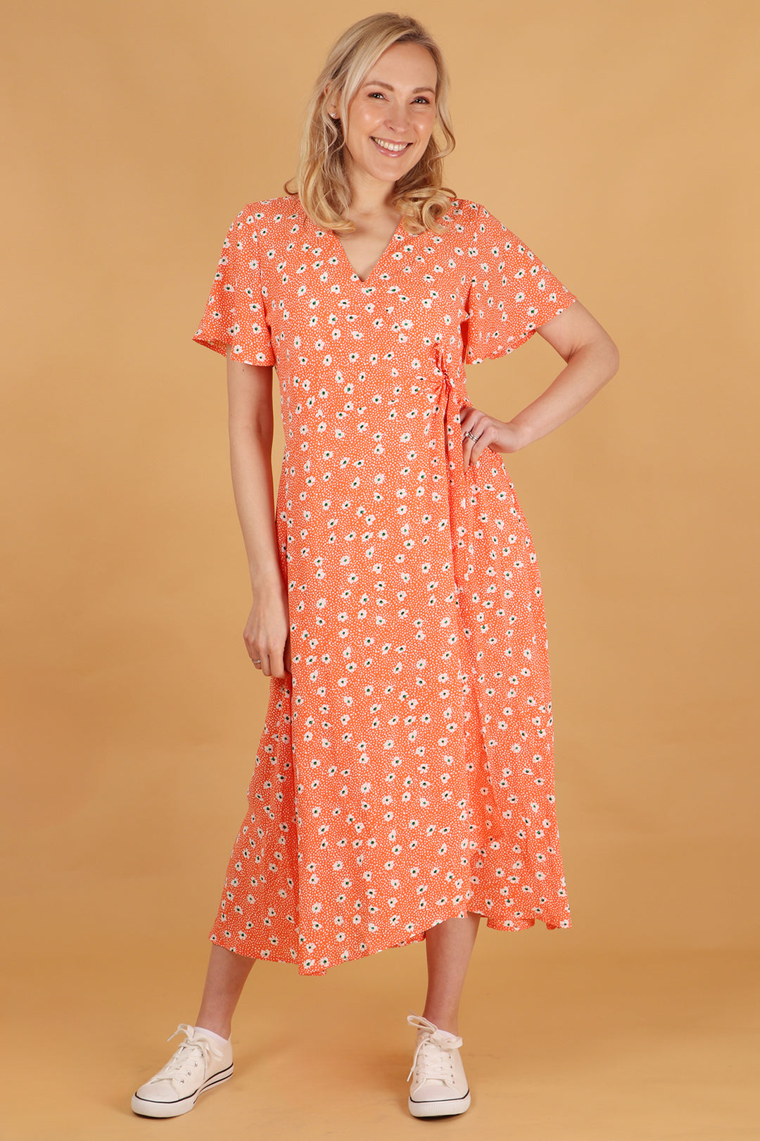 model wearing an orange daisy print waist tie wrap dress with short sleeves