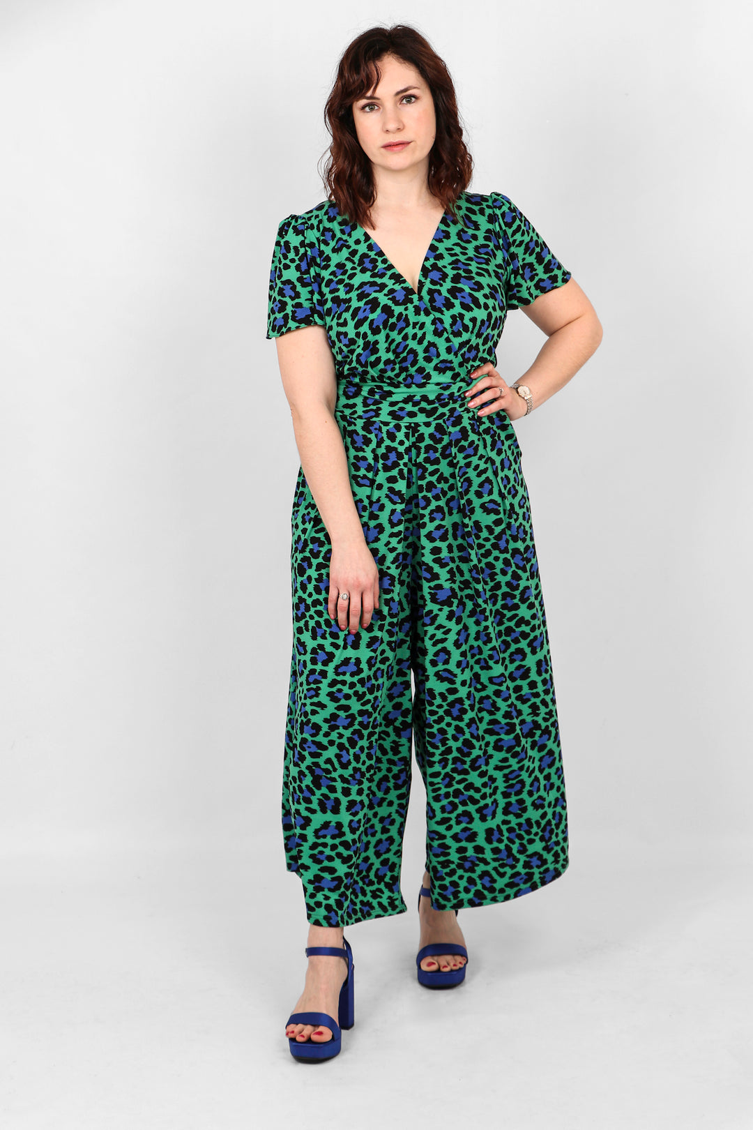 Model showing green and navy blue short sleeve jumpsuit in a cropped wide leg